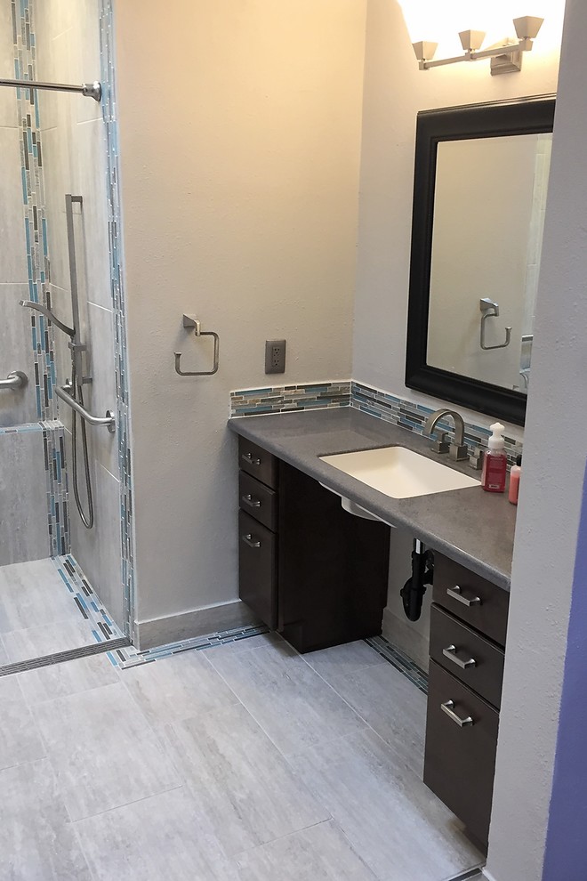 Inspiration for a mid-sized transitional kids bathroom in Phoenix with flat-panel cabinets, black cabinets, an alcove shower, a one-piece toilet, beige tile, blue tile, brown tile, gray tile, ceramic tile, grey walls, porcelain floors, an undermount sink and solid surface benchtops.