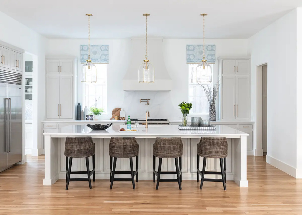 Design ideas for an expansive transitional u-shaped eat-in kitchen in Dallas with white cabinets, white splashback, light hardwood floors, with island and white benchtop.