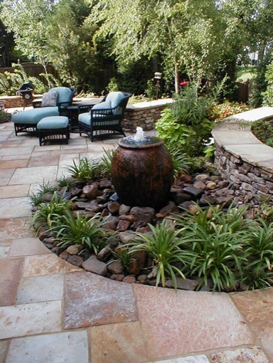 This is an example of a large modern backyard patio in Baltimore with a water feature, natural stone pavers and no cover.