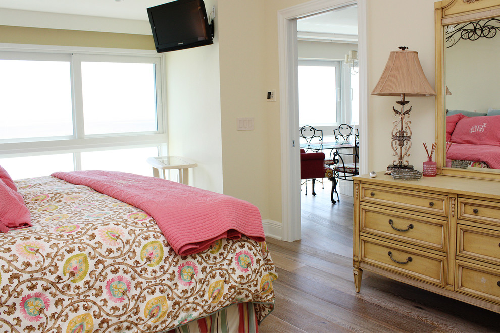 Photo of an expansive beach style master bedroom in Tampa with yellow walls, light hardwood floors and no fireplace.