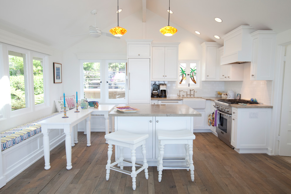 This is an example of a traditional l-shaped kitchen in Orange County with a farmhouse sink, recessed-panel cabinets, white cabinets, white splashback, subway tile splashback and dark hardwood floors.