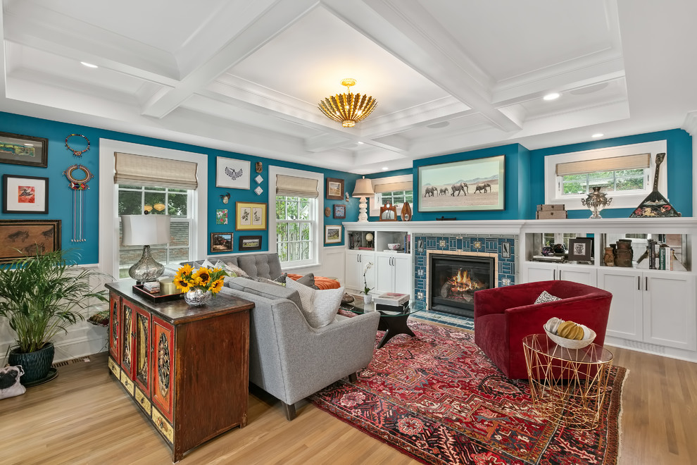 Design ideas for a mid-sized eclectic enclosed family room in Minneapolis with blue walls, light hardwood floors, a standard fireplace, a tile fireplace surround, a wall-mounted tv and brown floor.
