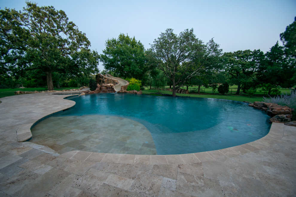 Modelo de piscina con tobogán natural rural grande a medida en patio trasero con adoquines de piedra natural