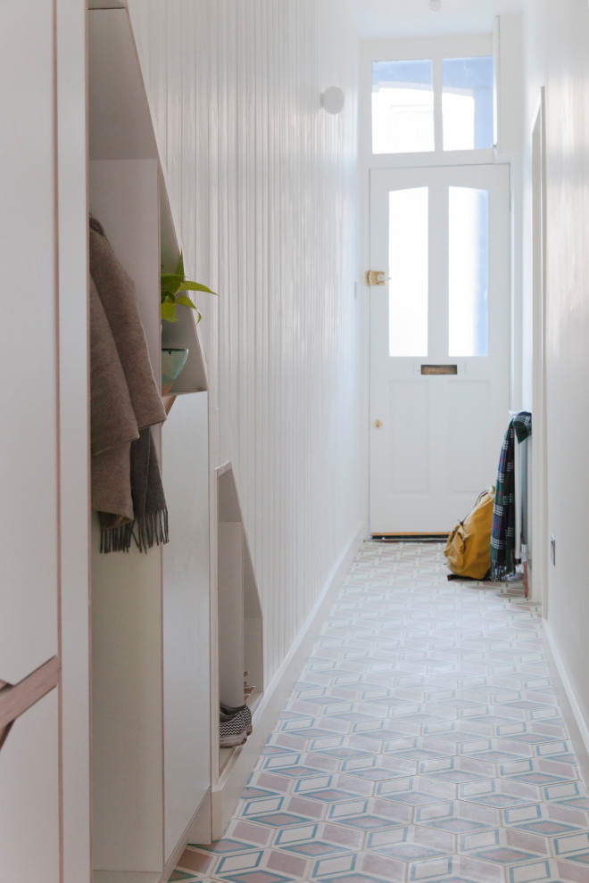 This is an example of a small contemporary hallway in London with white walls, ceramic floors and multi-coloured floor.