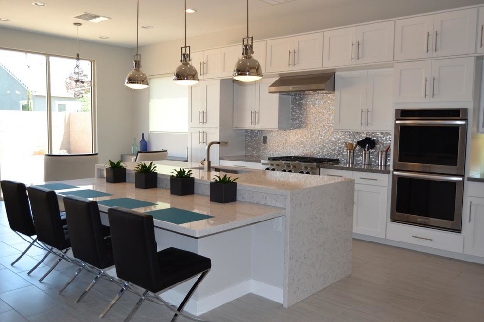 Mid-sized transitional single-wall porcelain tile and beige floor eat-in kitchen photo in Phoenix with an undermount sink, shaker cabinets, white cabinets, marble countertops, metallic backsplash, stainless steel appliances and an island