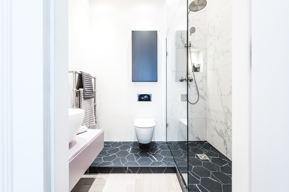 Photo of a mid-sized contemporary master wet room bathroom in London with flat-panel cabinets, white cabinets, an alcove tub, a wall-mount toilet, white tile, marble, white walls, a vessel sink, multi-coloured floor, an open shower, white benchtops and a niche.
