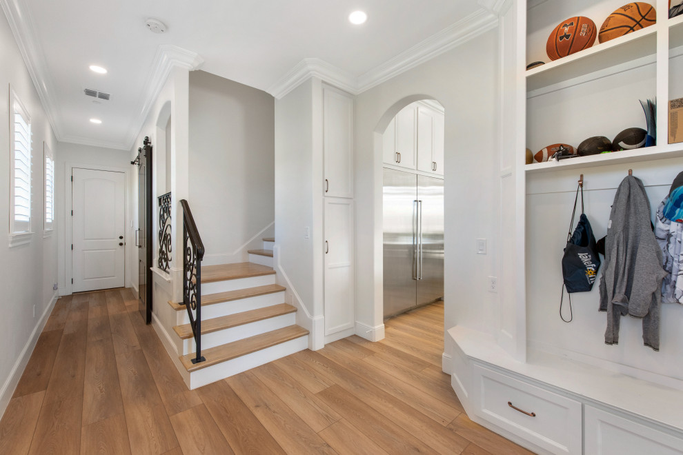 Mid-sized transitional light wood floor and vaulted ceiling hallway photo in Dallas with white walls