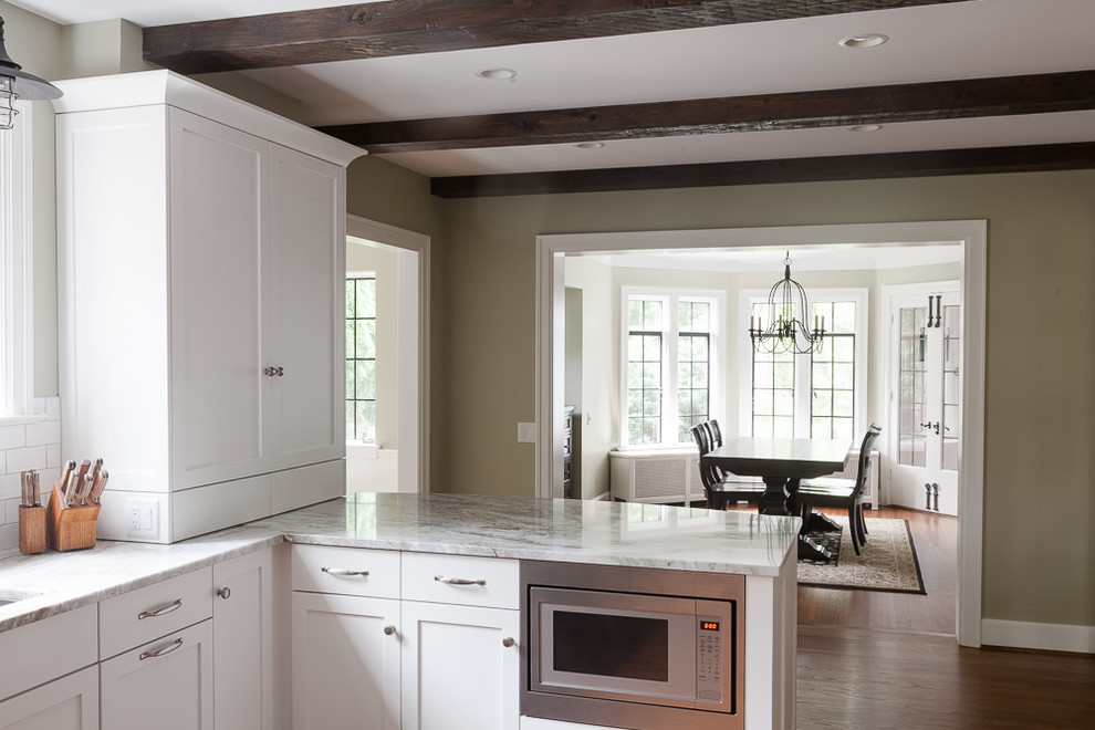 Inspiration for a mid-sized transitional u-shaped medium tone wood floor enclosed kitchen remodel with an undermount sink, shaker cabinets, white cabinets, quartzite countertops, white backsplash, subway tile backsplash, stainless steel appliances and a peninsula