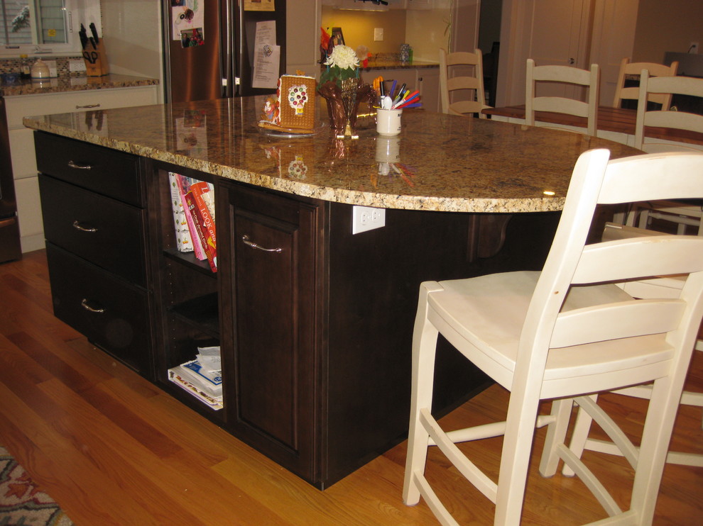Example of a transitional l-shaped light wood floor eat-in kitchen design in Boston with granite countertops, stainless steel appliances, an island, an undermount sink, raised-panel cabinets, white cabinets, beige backsplash and ceramic backsplash