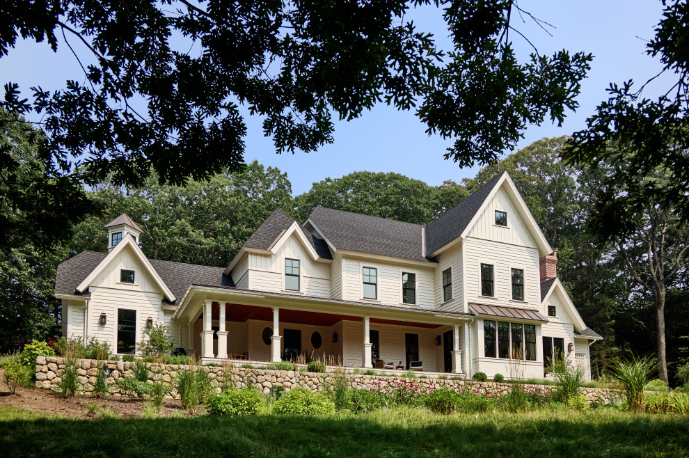 Cette image montre une grande façade de maison blanche rustique avec un toit en shingle et un toit noir.