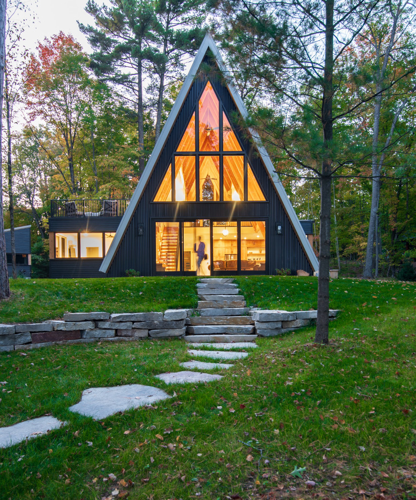 Réalisation d'une petite façade de Tiny House noire minimaliste avec un revêtement mixte, un toit à deux pans, un toit en métal et un toit gris.