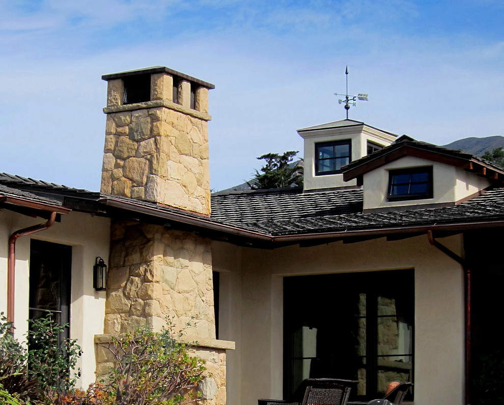 This is an example of a mid-sized country one-storey beige house exterior in Santa Barbara with stone veneer, a gable roof and a tile roof.