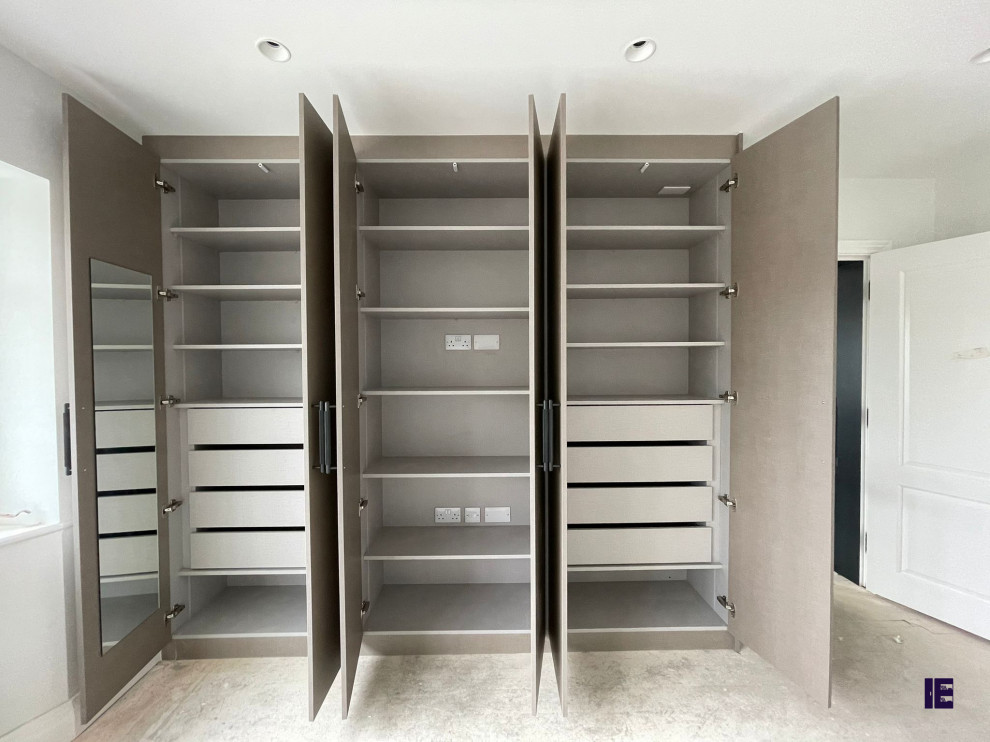 Ejemplo de armario y vestidor minimalista pequeño con a medida, armarios con paneles con relieve, puertas de armario grises y suelo blanco