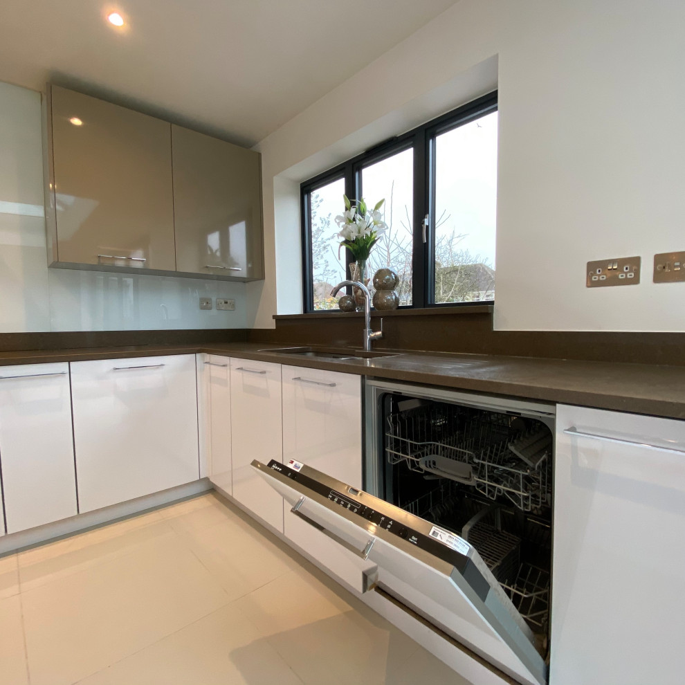 Photo of a medium sized contemporary open plan kitchen in Berkshire with a single-bowl sink, flat-panel cabinets, white cabinets, quartz worktops, white splashback, stainless steel appliances, porcelain flooring, multiple islands and brown worktops.