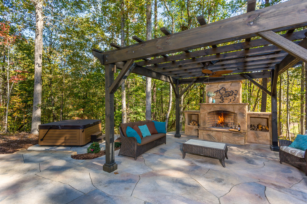 This is an example of a large modern backyard patio in Raleigh with an outdoor kitchen, stamped concrete and a pergola.