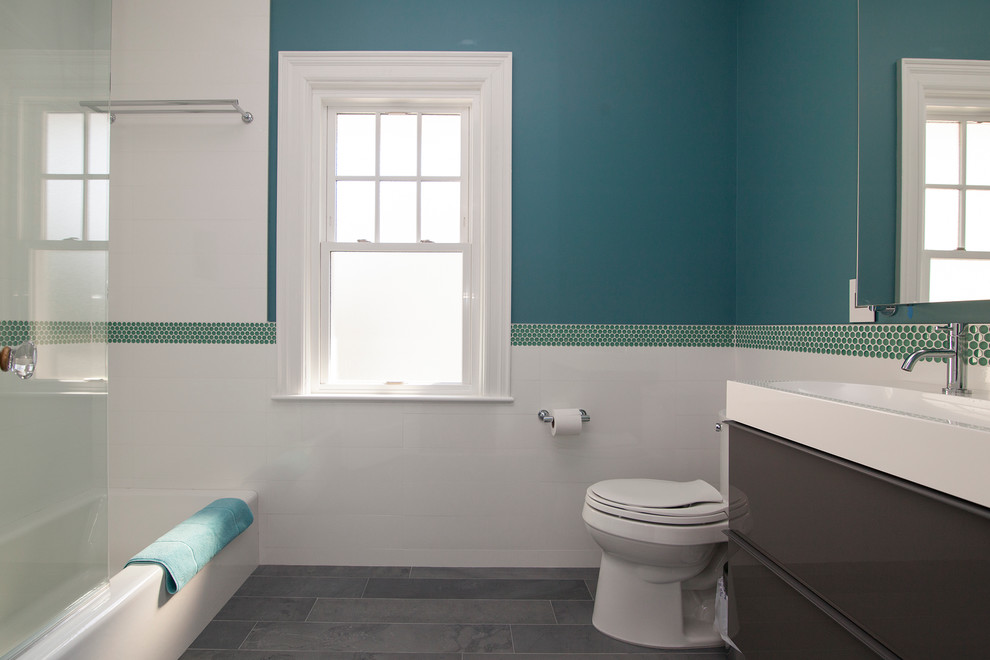Design ideas for a mid-sized transitional kids bathroom in New York with an alcove tub, a shower/bathtub combo, a trough sink, a one-piece toilet, blue walls and porcelain floors.