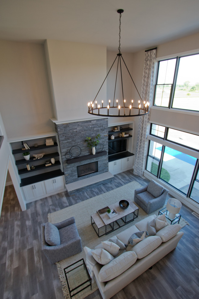 Photo of a large formal open concept living room in Other with beige walls, vinyl floors, a standard fireplace, a corner tv, grey floor and vaulted.