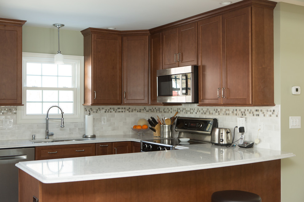 Example of a mid-sized transitional l-shaped ceramic tile and white floor eat-in kitchen design with an undermount sink, quartz countertops, white backsplash, porcelain backsplash, stainless steel appliances, white countertops, shaker cabinets, medium tone wood cabinets and a peninsula