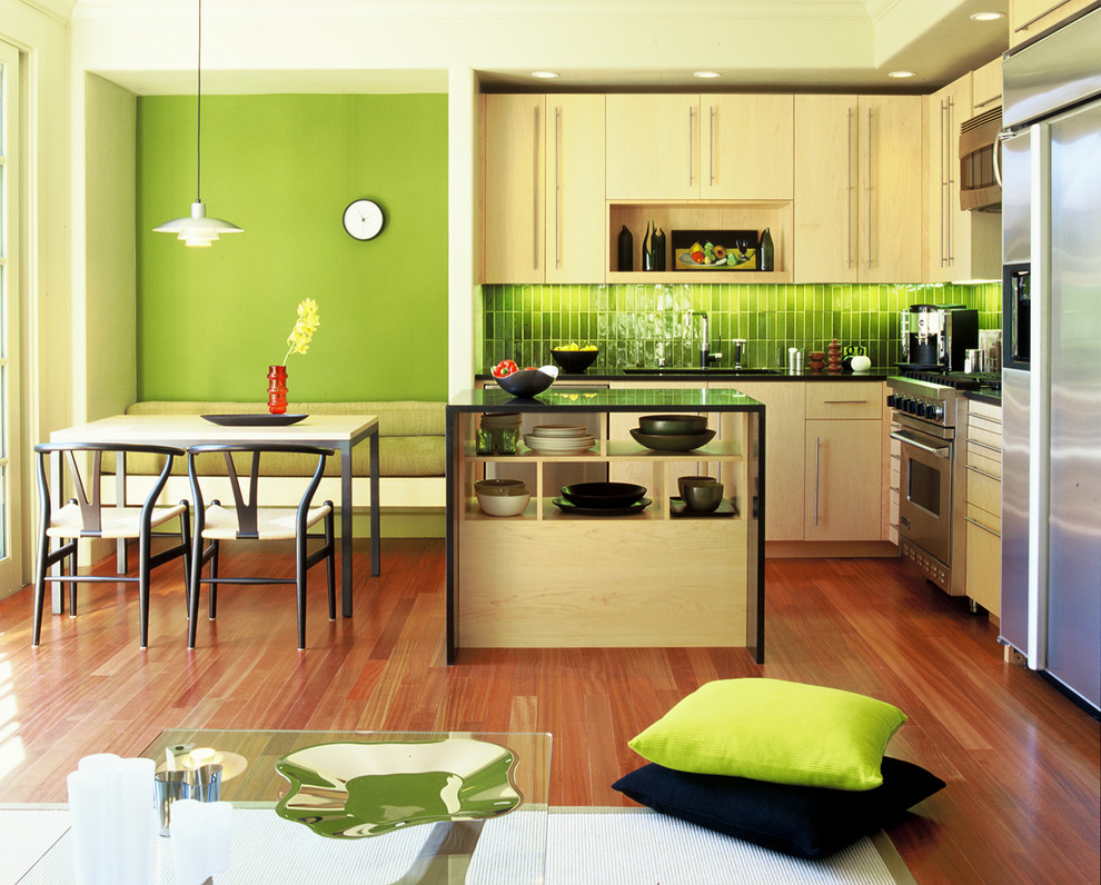 This is an example of a modern l-shaped eat-in kitchen in San Francisco with stainless steel appliances, an undermount sink, flat-panel cabinets, light wood cabinets and green splashback.