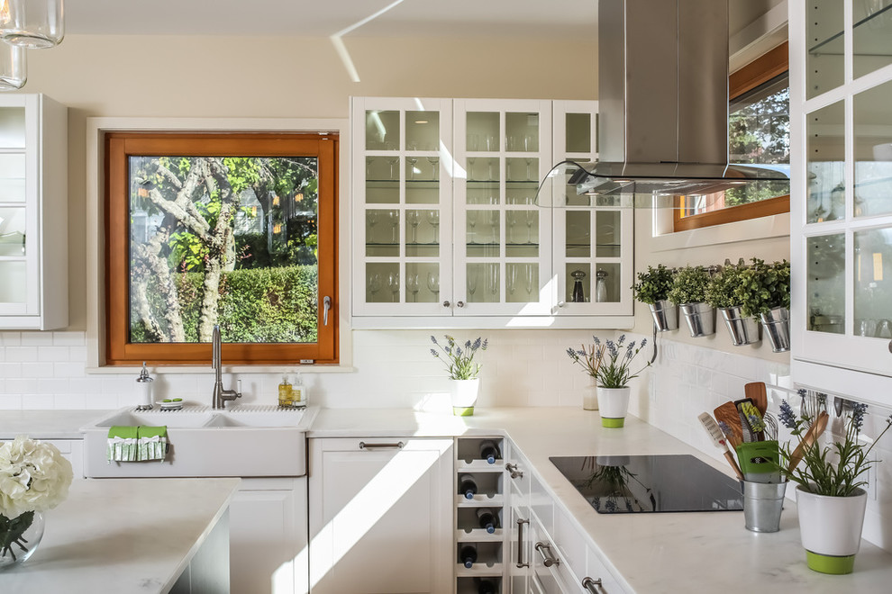 Inspiration for a transitional l-shaped kitchen in New York with a farmhouse sink, glass-front cabinets, white cabinets, marble benchtops, white splashback, subway tile splashback and with island.