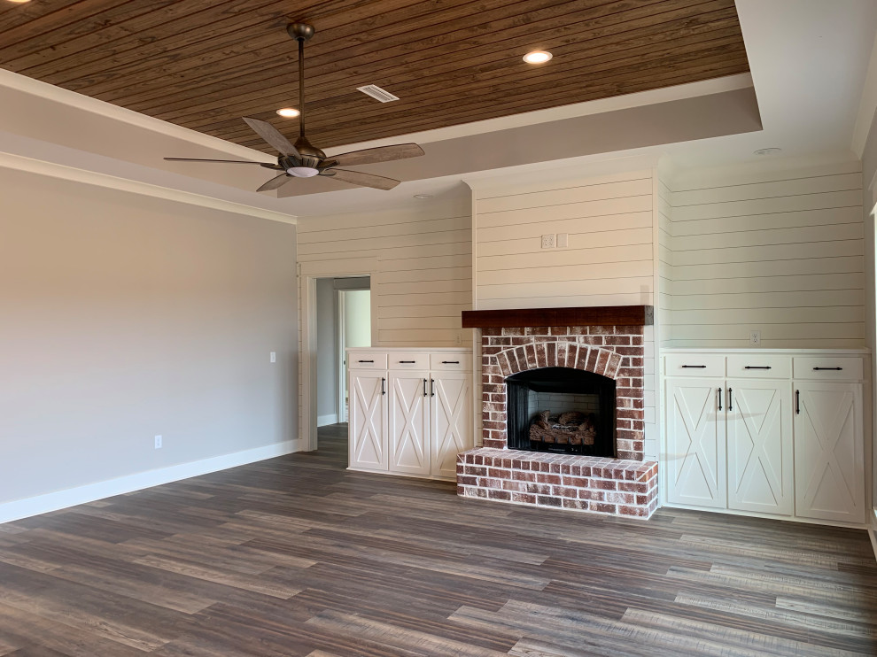 This is an example of a large classic enclosed living room in Other with white walls, vinyl flooring, a standard fireplace, a brick fireplace surround, a wall mounted tv, multi-coloured floors, a coffered ceiling and tongue and groove walls.