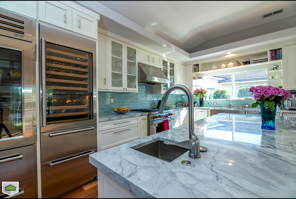 Large beach style l-shaped eat-in kitchen in San Francisco with an undermount sink, shaker cabinets, white cabinets, marble benchtops, green splashback, glass tile splashback, stainless steel appliances, medium hardwood floors and with island.