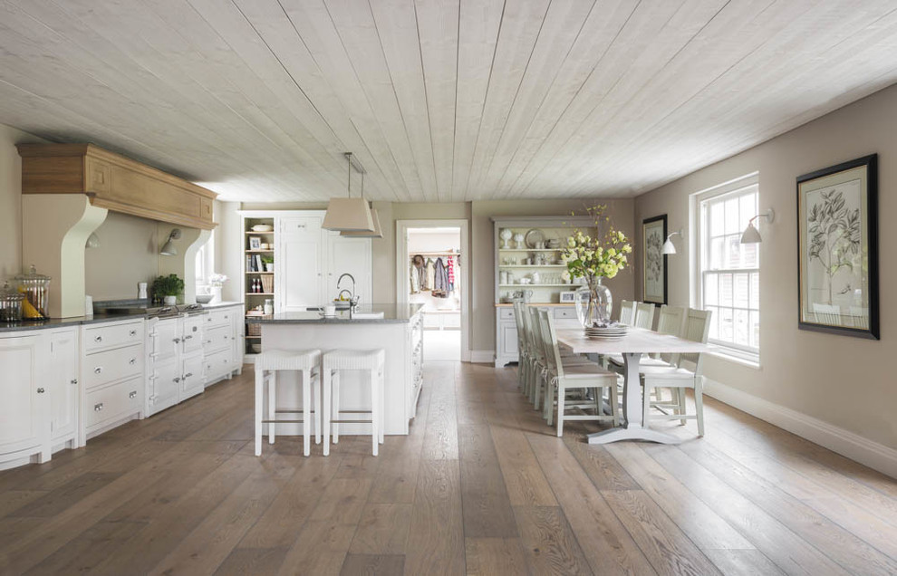 This is an example of a country open plan kitchen in Hampshire with light hardwood floors and with island.