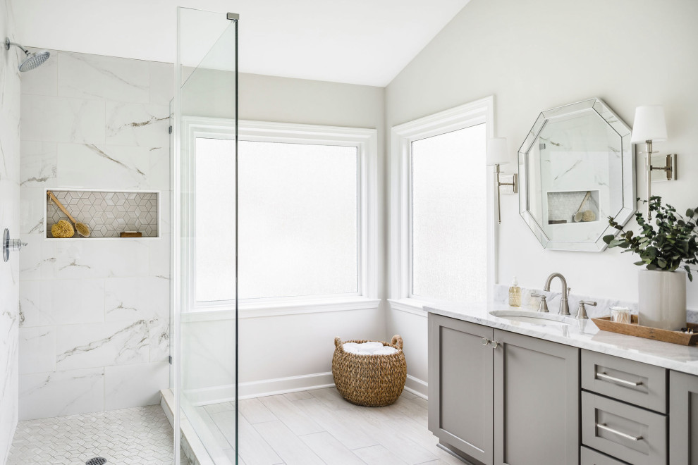 Large traditional master bathroom in Charlotte with shaker cabinets, grey cabinets, a corner shower, a two-piece toilet, white tile, porcelain tile, white walls, porcelain floors, an undermount sink, marble benchtops, beige floor, a hinged shower door and grey benchtops.