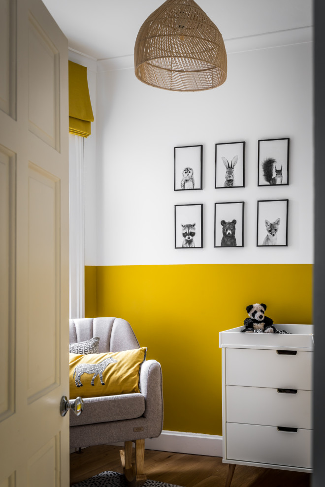 Inspiration pour une petite chambre de bébé neutre avec un mur jaune et un sol en bois brun.