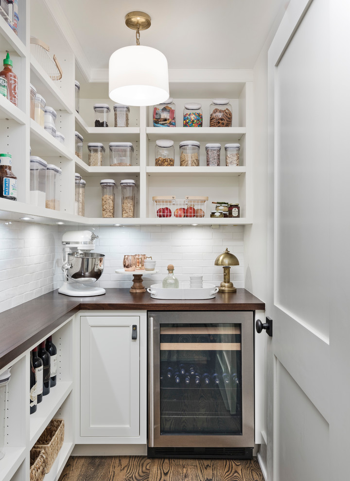 This is an example of a transitional l-shaped kitchen pantry in Detroit with open cabinets, white cabinets, wood benchtops, white splashback, stainless steel appliances, dark hardwood floors, brown floor and brown benchtop.