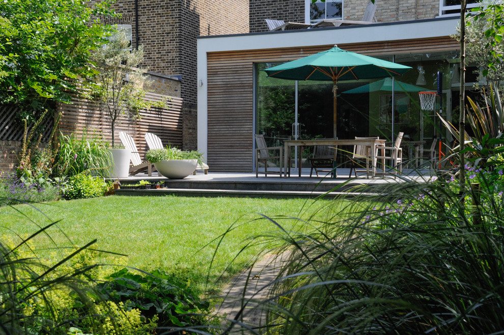 Design ideas for a mid-sized contemporary backyard patio in London with concrete slab.