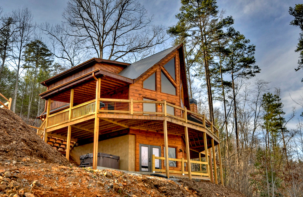 This is an example of a large country three-storey brown house exterior in Atlanta with wood siding, a gable roof and a metal roof.