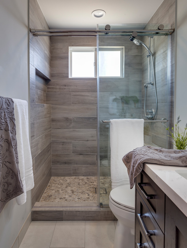 Design ideas for a mid-sized transitional master bathroom in Los Angeles with shaker cabinets, dark wood cabinets, an alcove shower, a two-piece toilet, gray tile, porcelain tile, grey walls, porcelain floors, an undermount sink, engineered quartz benchtops, grey floor and a sliding shower screen.