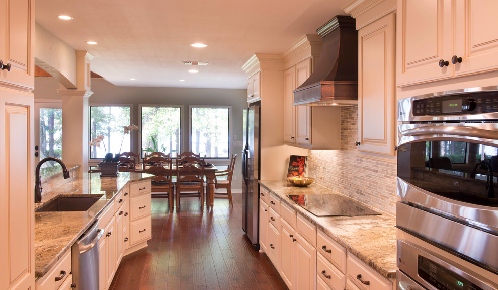 Transitional galley open concept kitchen photo in New Orleans with an undermount sink, raised-panel cabinets, white cabinets, granite countertops, gray backsplash, mosaic tile backsplash and stainless steel appliances