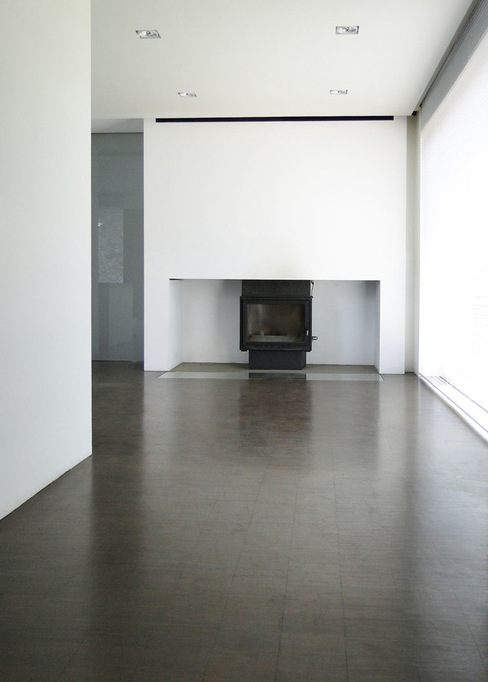 Mittelgroße, Offene Moderne Bibliothek mit weißer Wandfarbe, dunklem Holzboden, Kamin, verputzter Kaminumrandung, verstecktem TV und braunem Boden in Bremen