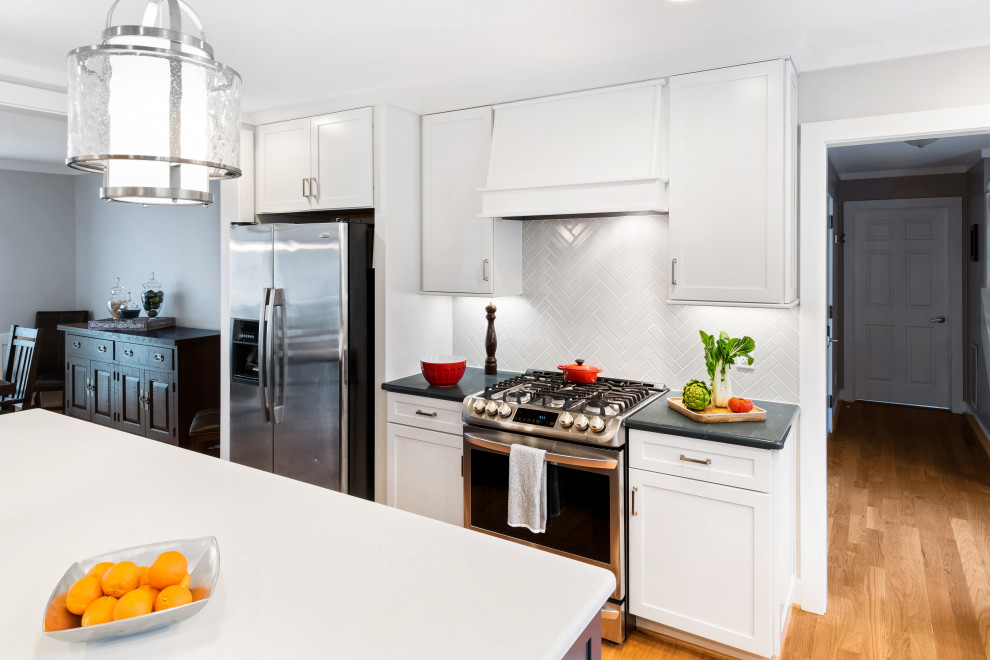 Mid-sized transitional l-shaped medium tone wood floor and brown floor eat-in kitchen photo in Raleigh with an undermount sink, shaker cabinets, white cabinets, quartz countertops, gray backsplash, porcelain backsplash, stainless steel appliances, an island and gray countertops