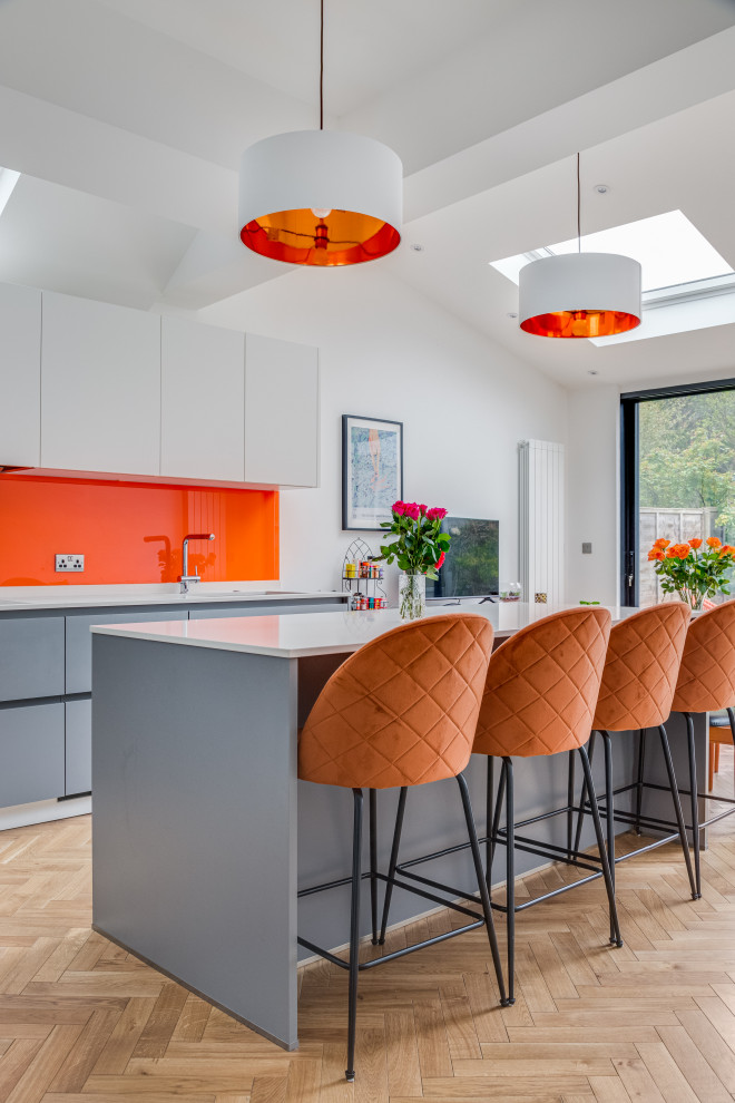 Inspiration for a large contemporary light wood floor, brown floor and vaulted ceiling eat-in kitchen remodel in London with a drop-in sink, gray cabinets, quartzite countertops, orange backsplash, glass sheet backsplash, colored appliances and white countertops