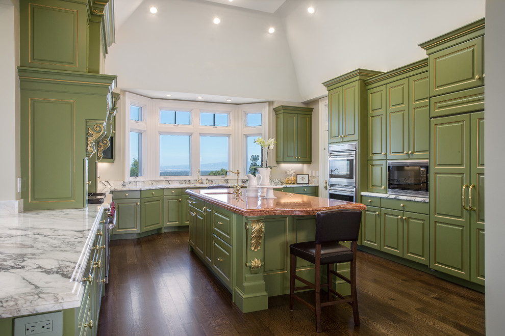 This is an example of an expansive traditional u-shaped eat-in kitchen in San Francisco with a drop-in sink, recessed-panel cabinets, green cabinets, granite benchtops, white splashback, stone slab splashback, stainless steel appliances, dark hardwood floors and multiple islands.