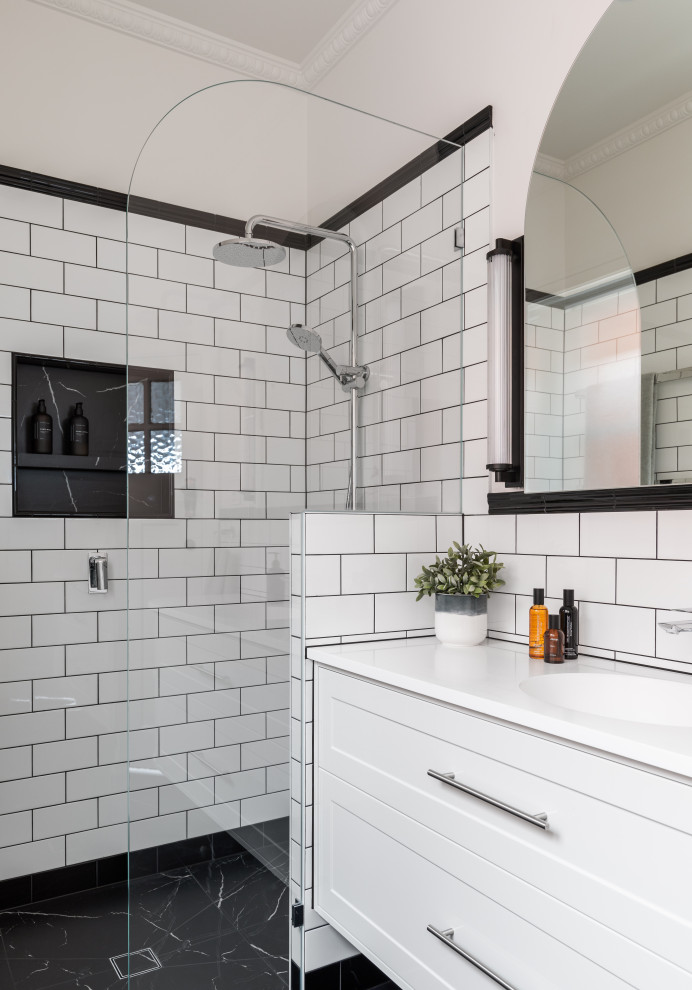 Идея дизайна: ванная комната среднего размера в стиле неоклассика (современная классика) с белыми фасадами, отдельно стоящей ванной, открытым душем, унитазом-моноблоком, черно-белой плиткой, керамической плиткой, белыми стенами, полом из керамогранита, монолитной раковиной, столешницей из искусственного камня, черным полом, открытым душем, белой столешницей, нишей, тумбой под одну раковину, подвесной тумбой, обоями на стенах и фасадами в стиле шейкер