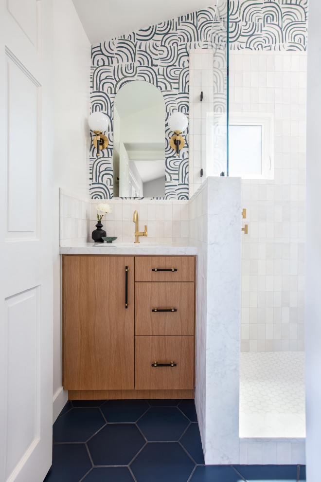 На фото: ванная комната в стиле модернизм с светлыми деревянными фасадами, открытым душем, унитазом-моноблоком, белой плиткой, керамогранитной плиткой, белыми стенами, полом из керамогранита, врезной раковиной, столешницей из искусственного кварца, синим полом, открытым душем, нишей, тумбой под одну раковину, встроенной тумбой, сводчатым потолком и обоями на стенах