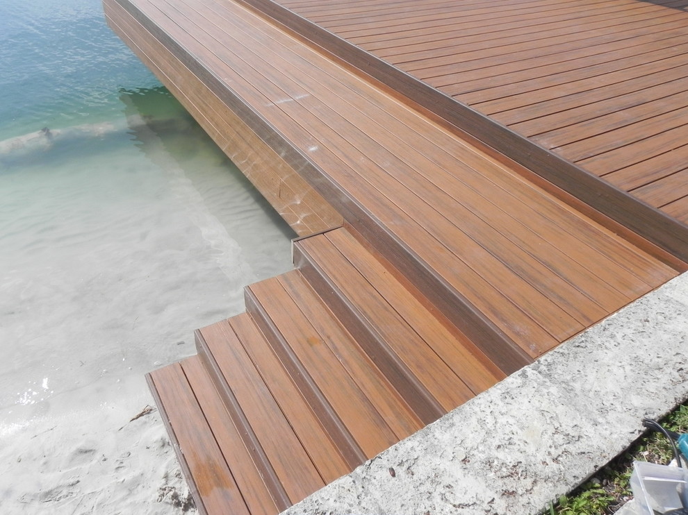 This is an example of a mid-sized beach style backyard deck in Miami with with dock and no cover.