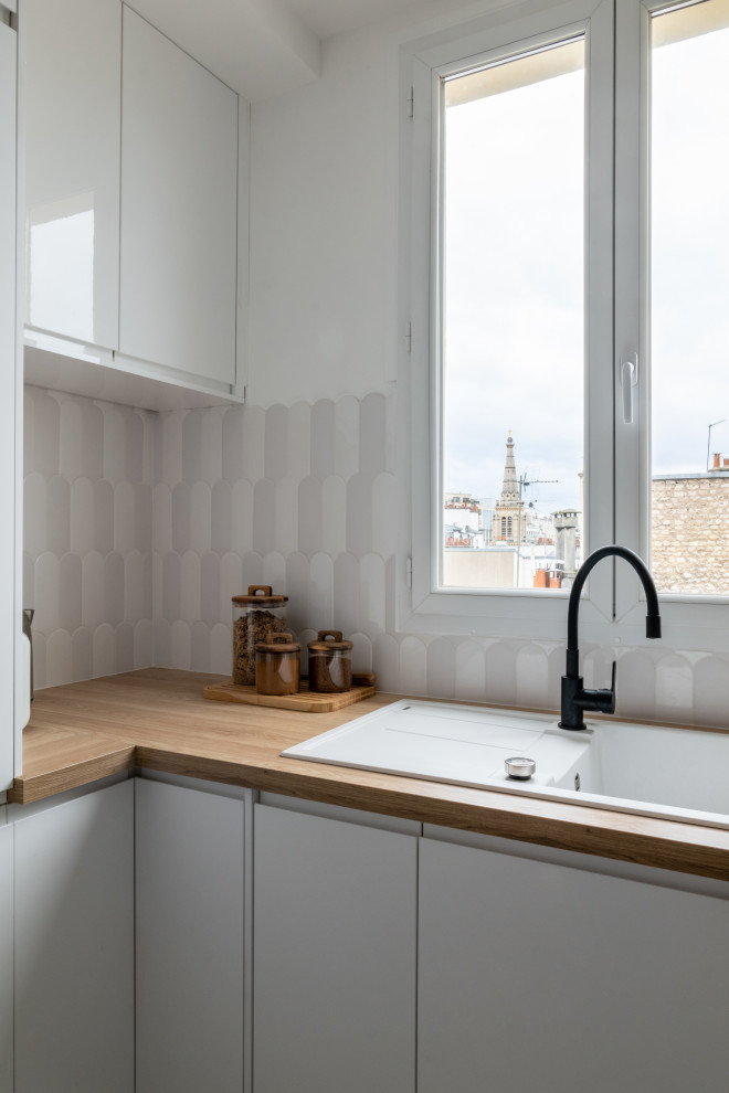 Esempio di una cucina scandinava di medie dimensioni con ante bianche, paraspruzzi bianco, elettrodomestici neri, parquet chiaro e top marrone
