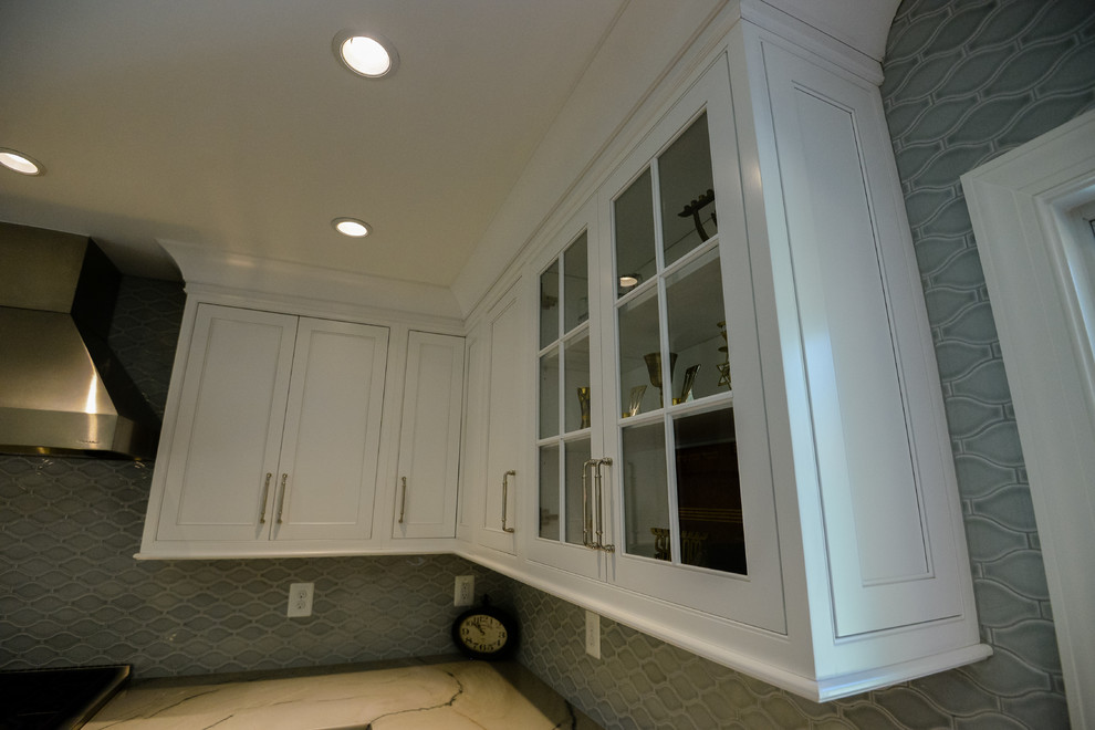 Example of a large transitional u-shaped medium tone wood floor and brown floor eat-in kitchen design in DC Metro with a farmhouse sink, recessed-panel cabinets, white cabinets, marble countertops, stainless steel appliances, an island, gray backsplash and porcelain backsplash