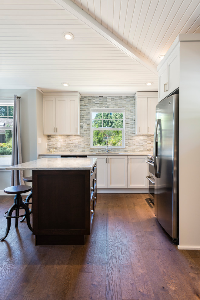 Small transitional l-shaped medium tone wood floor and brown floor open concept kitchen photo in Vancouver with an undermount sink, recessed-panel cabinets, white cabinets, quartzite countertops, gray backsplash, matchstick tile backsplash, stainless steel appliances and an island