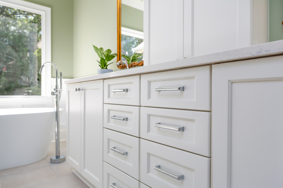 Example of a mid-sized transitional master gray tile and porcelain tile porcelain tile, gray floor and double-sink freestanding bathtub design with flat-panel cabinets, white cabinets, a two-piece toilet, green walls, an undermount sink, quartz countertops, a hinged shower door, white countertops and a built-in vanity