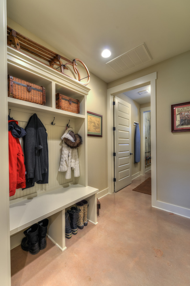 Photo of a mid-sized mudroom in Austin with beige walls, concrete floors and a white front door.