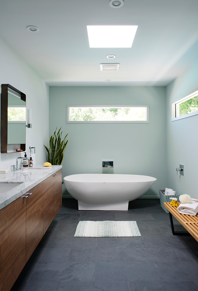 Inspiration for a large midcentury master bathroom in Los Angeles with flat-panel cabinets, dark wood cabinets, marble benchtops, a freestanding tub, blue walls, slate floors, an undermount sink, gray tile and grey floor.