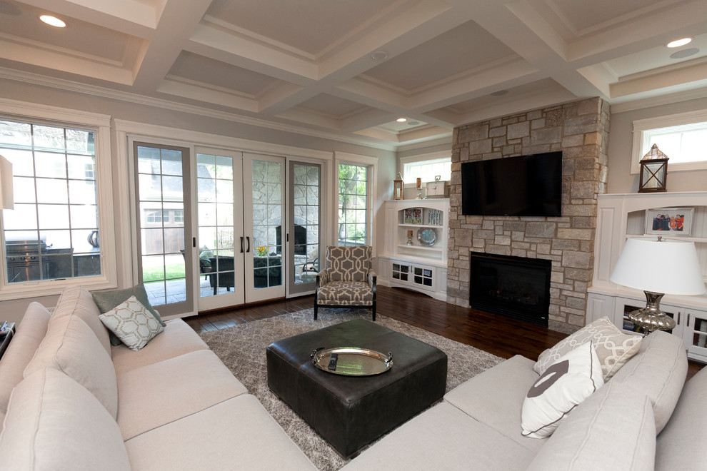 Inspiration for a large country open concept family room in Chicago with grey walls, dark hardwood floors, a standard fireplace, a stone fireplace surround, a wall-mounted tv and brown floor.