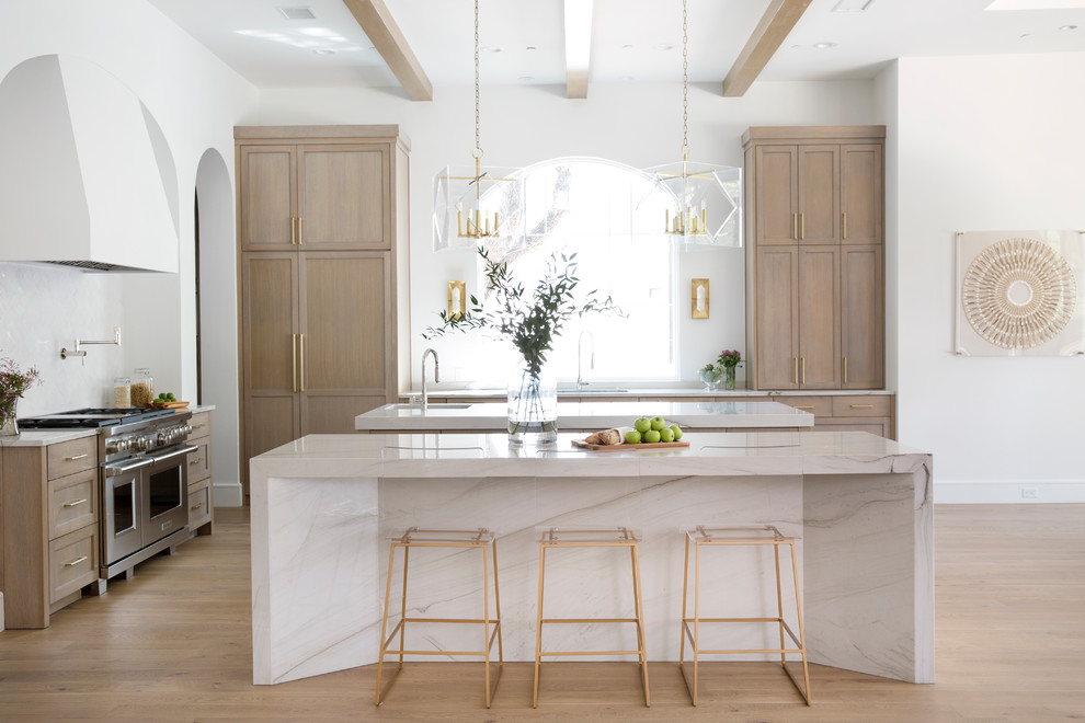 Photo of a mediterranean kitchen in Austin with an undermount sink, shaker cabinets, light wood cabinets, stainless steel appliances, light hardwood floors, multiple islands and white benchtop.