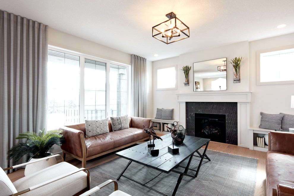 Photo of a mid-sized transitional open concept living room in Calgary with white walls, medium hardwood floors, a standard fireplace, a tile fireplace surround, no tv and brown floor.